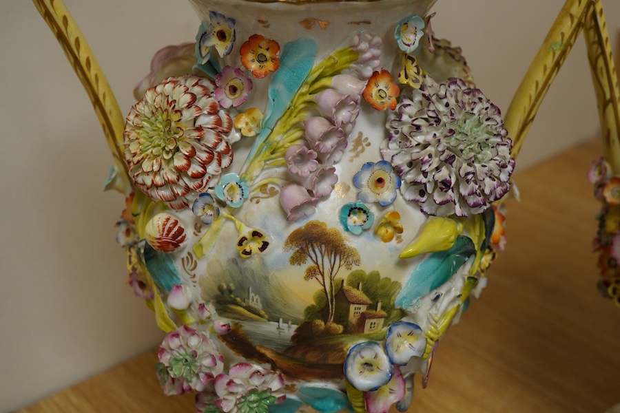 A pair of English porcelain floral encrusted vases and covers, c.1830, possibly Samuel Alcock, each painted with landscapes, 44cm high